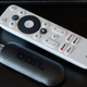A photo of the Onn FHD Streaming Stick laying next to the Onn remote